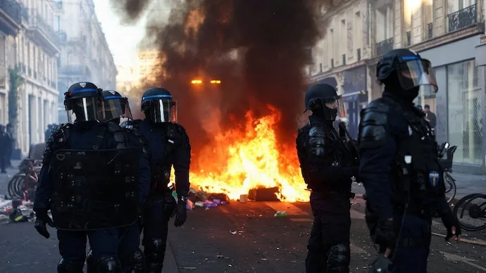 Police officers stand near a fire during protests over rising living costs and fuel prices in Paris, France