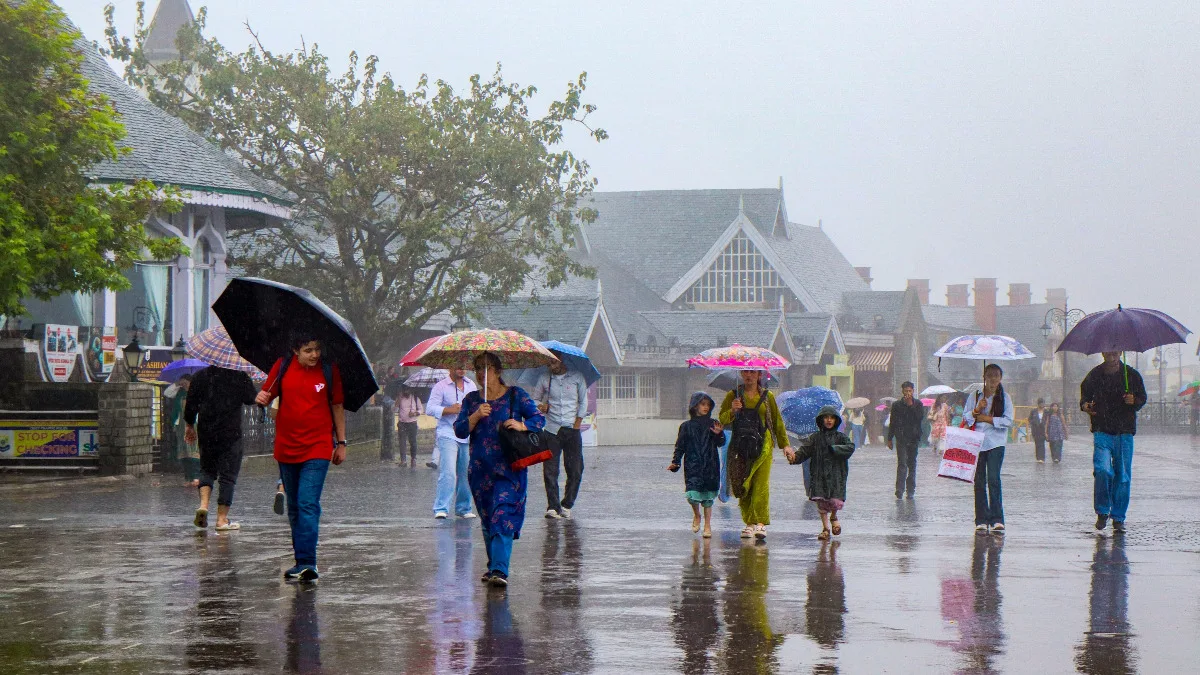 People walking with umbrellas during rainfall as the southwest monsoon withdraws from parts of India.
